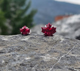 Red maple leaf earrings on a rock with a blurred natural background
