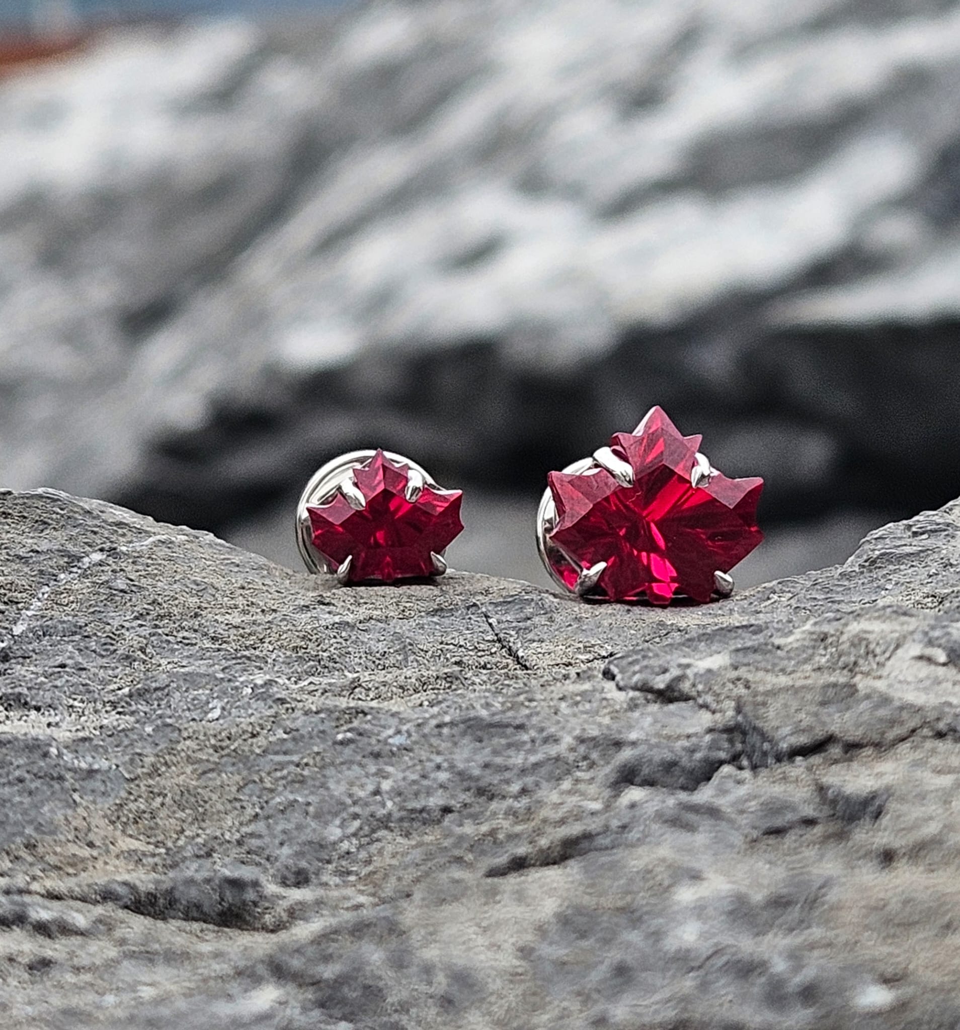 Red gemstone earrings on a rocky surface